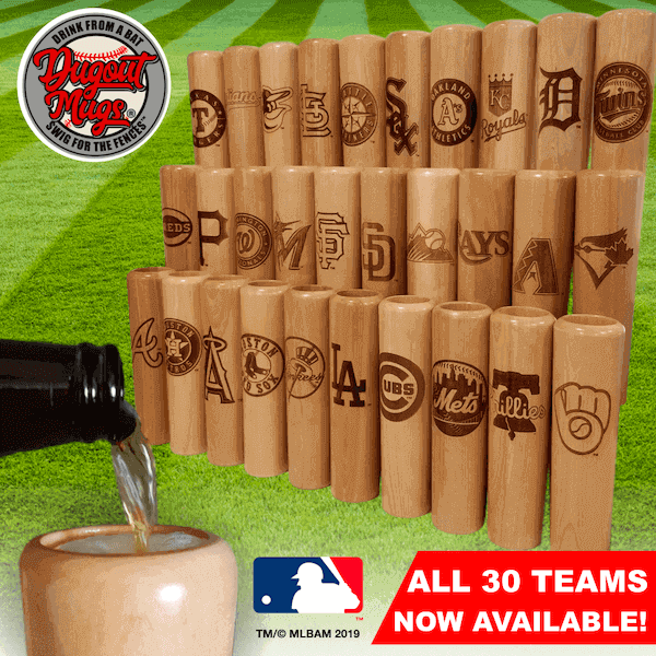 Wooden mugs with MLB team logos on a grass background, with a bottle pouring liquid into one mug.