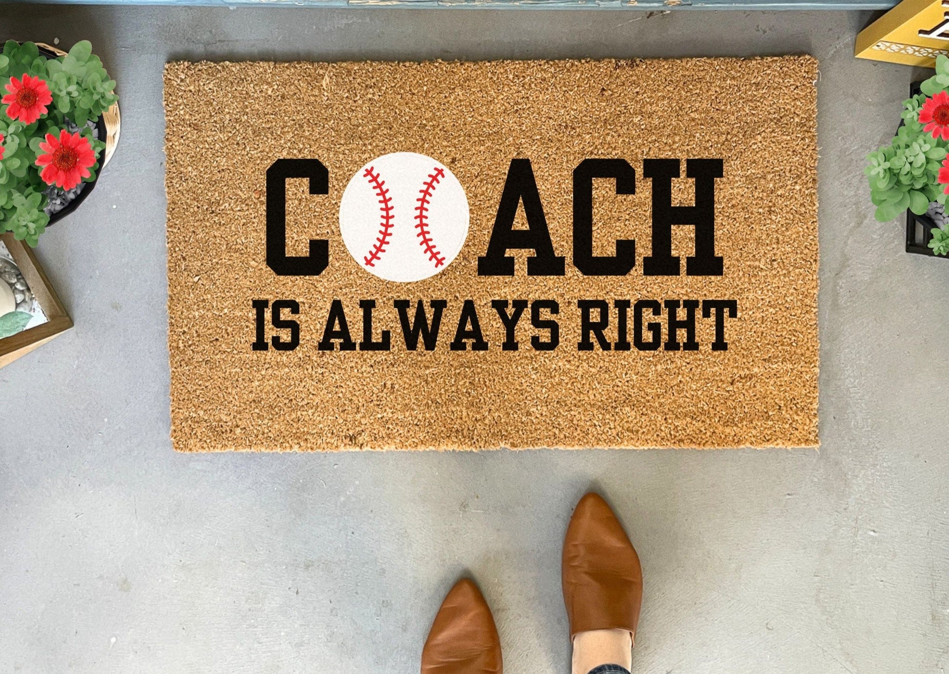 Doormat with 'Coach is Always Right' text and baseball graphic on a concrete floor.