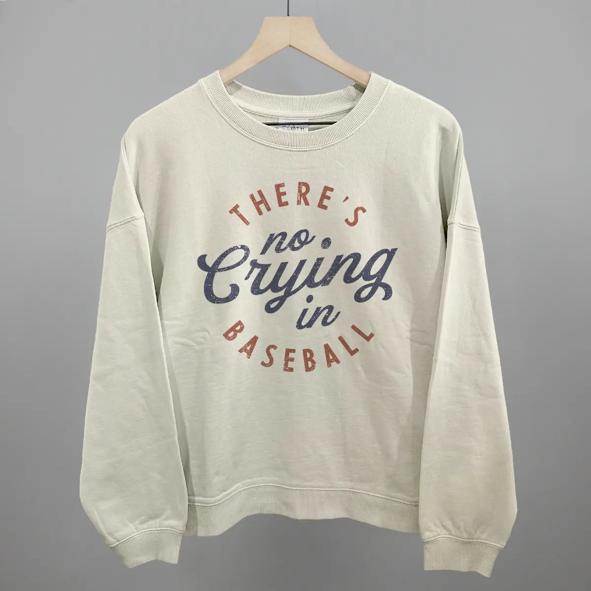 Collection of Beige sweatshirt with 'There's no crying in baseball' text on a gray background in a gallery layout