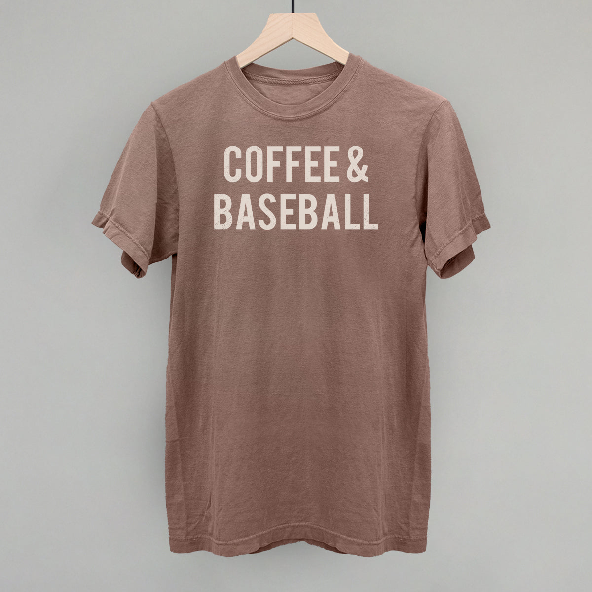 Collection of Brown comfort colors t-shirt with 'COFFEE & BASEBALL' text on a hanger against a gray background in a gallery layout