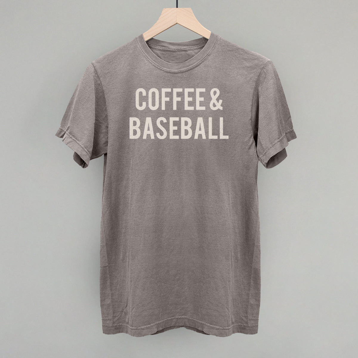 Gray comfort colors t-shirt with 'COFFEE & BASEBALL' text on a hanger against a gray background