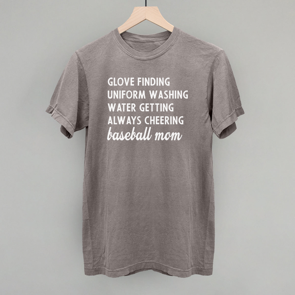 Gray comfort color t-shirt with white text on a wooden hanger against a gray background