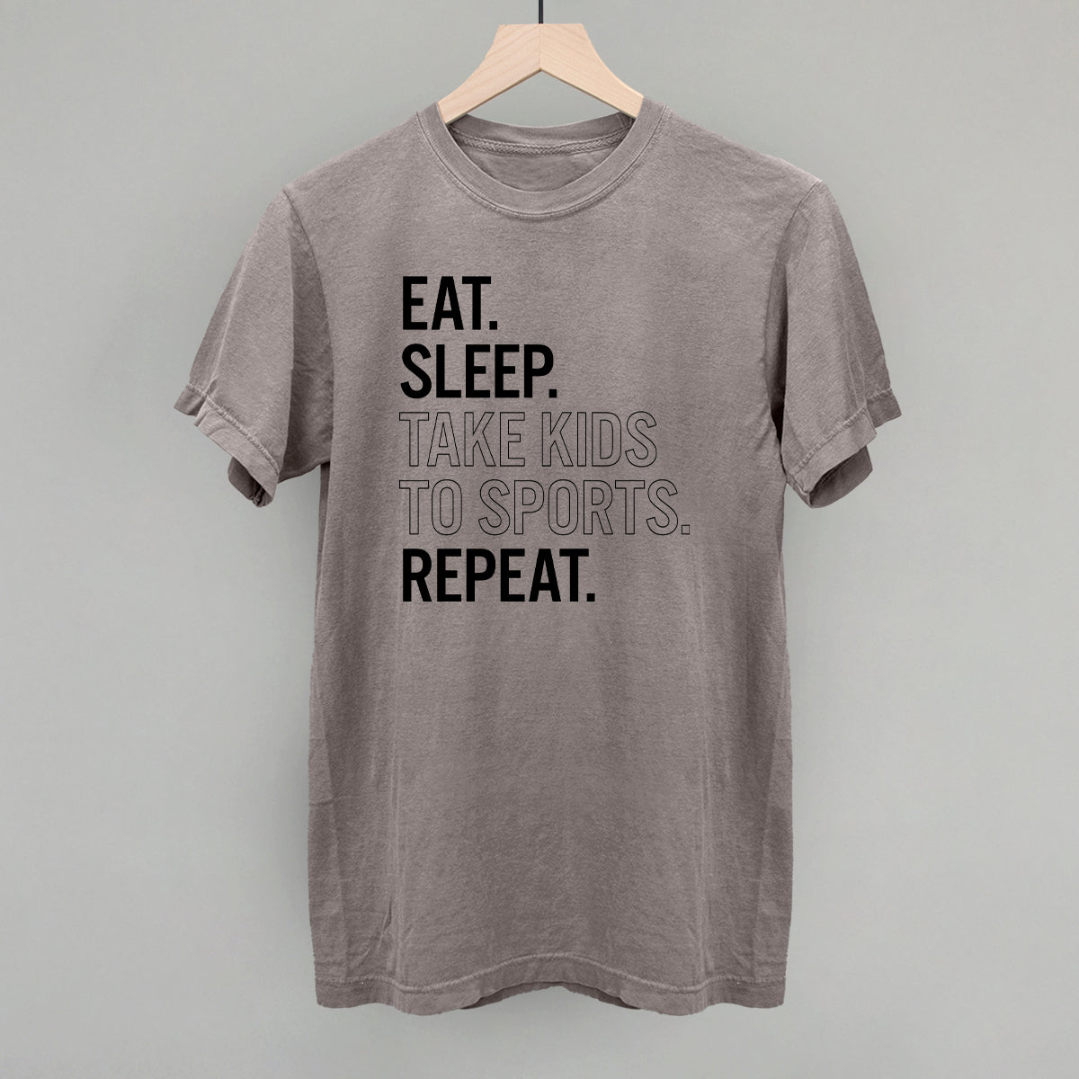 Collection of Gray comfort colors  t-shirt with text 'EAT. SLEEP. TAKE KIDS TO SPORTS. REPEAT.' on a hanger against a gray background in a gallery layout