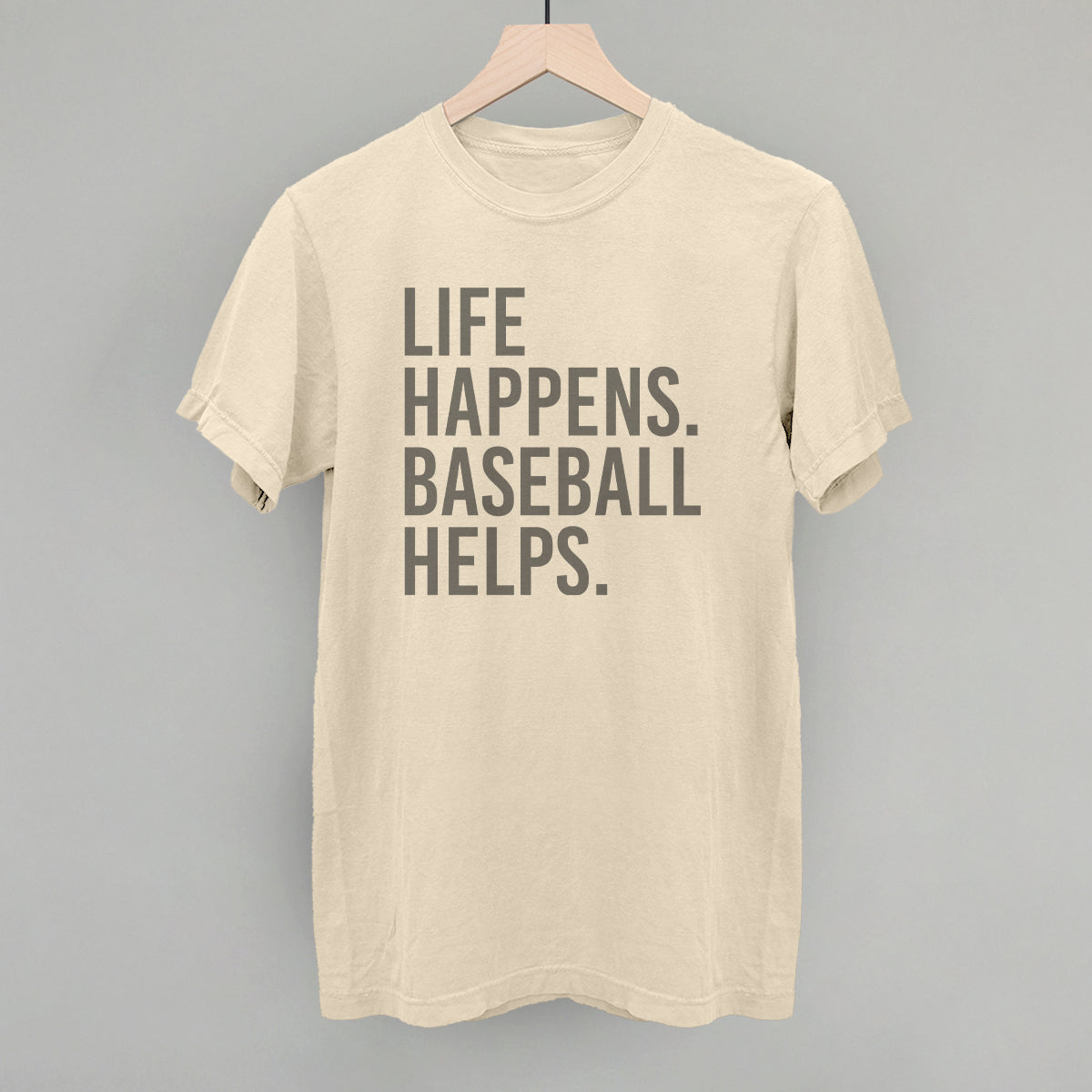 Collection of Beige t-shirt with 'Life happens. Baseball helps.' text on a gray background in a gallery layout