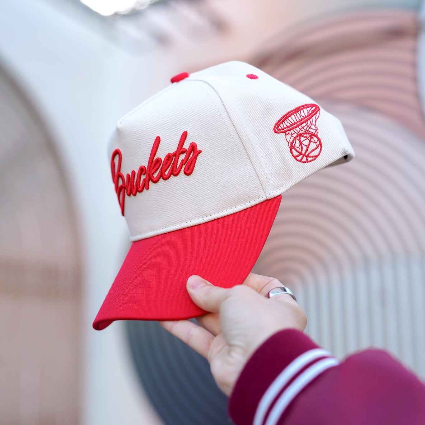 Collection of Red and white cap with 'Buckeyes' text held by a person wearing a maroon jacket. in a gallery layout