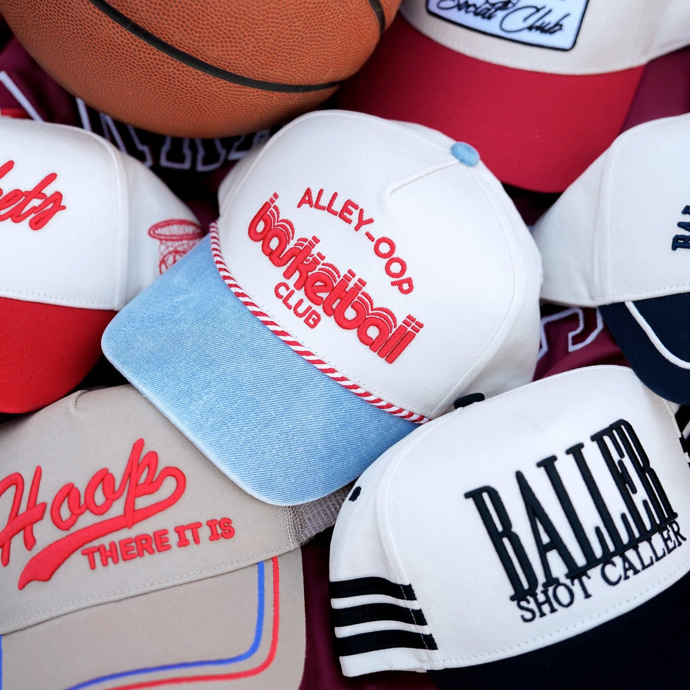 Collection of Collection of sports-themed hats and a basketball on a colorful background in a gallery layout