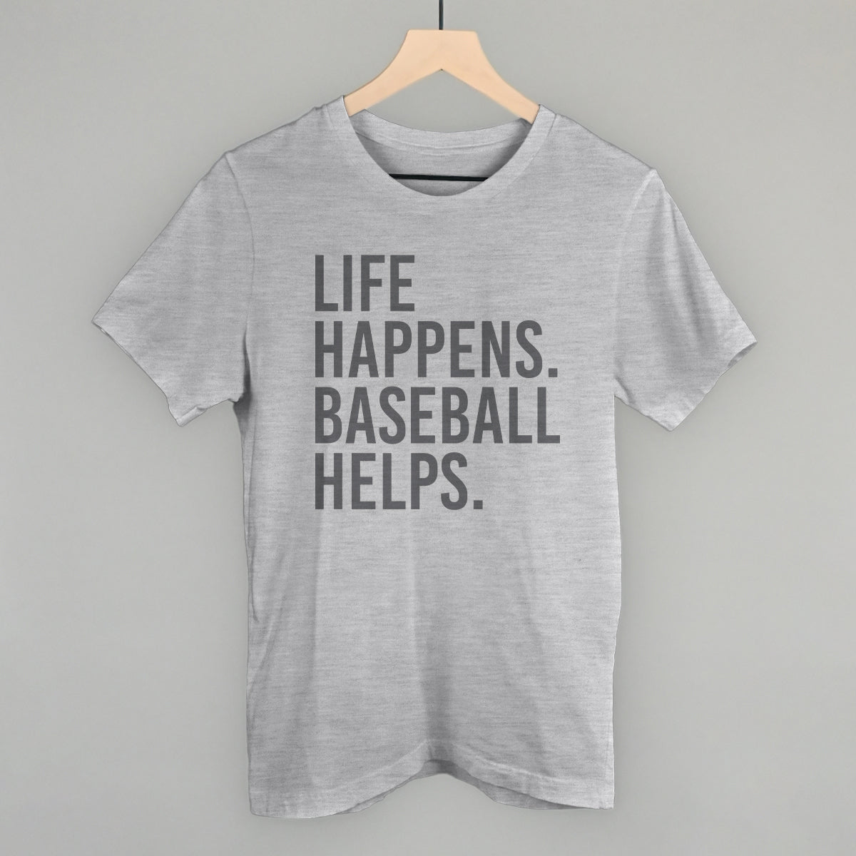 Gray t-shirt with 'Life happens. Baseball helps.' text on a hanger against a gray background