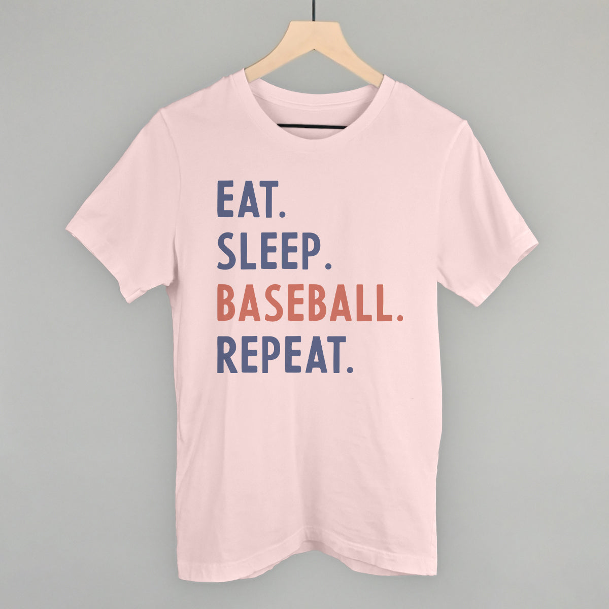 Collection of Pink t-shirt with 'Eat. Sleep. Baseball. Repeat.' text on a hanger against a gray background in a gallery layout
