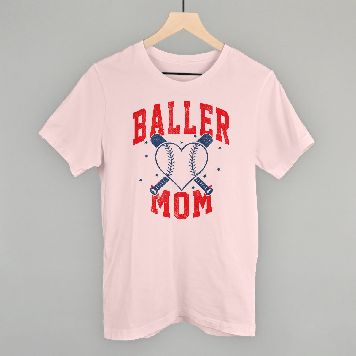 Collection of Pink t-shirt with 'Baller Mom' text on a hanger against a gray background in a gallery layout