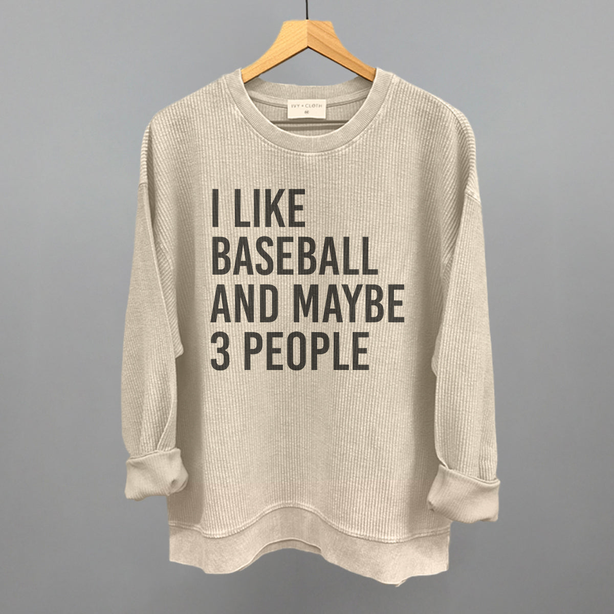 Moonbeam sweatshirt with text 'I LIKE BASEBALL AND MAYBE 3 PEOPLE' on a hanger against a gray background