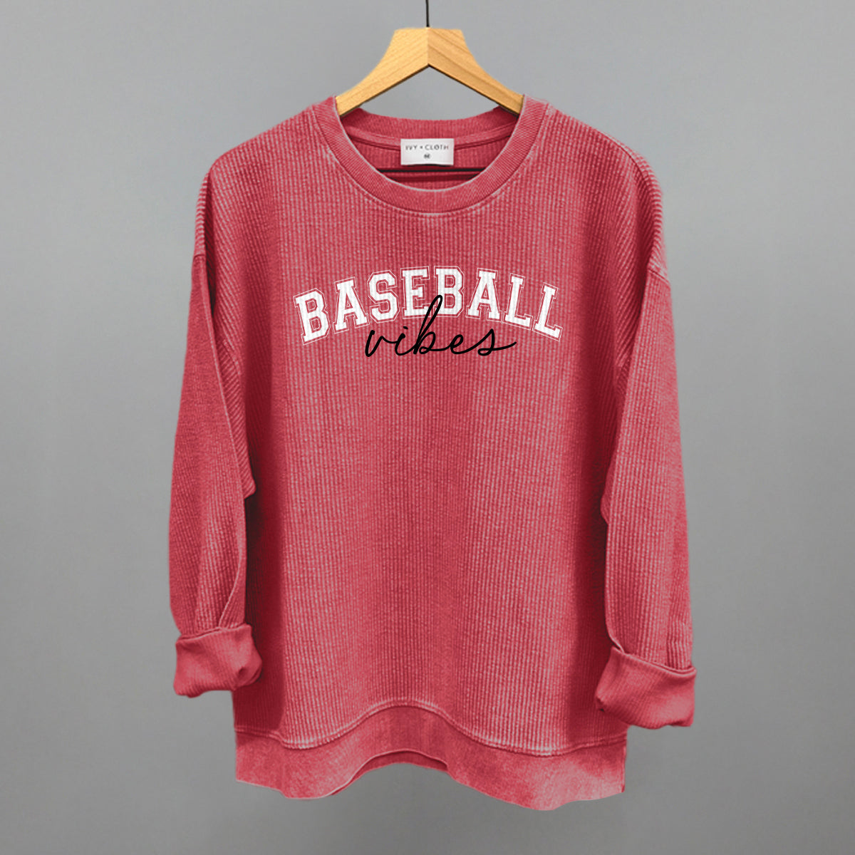 Collection of Red sweatshirt with 'BASEBALL vibes' text on a hanger against a gray background in a gallery layout