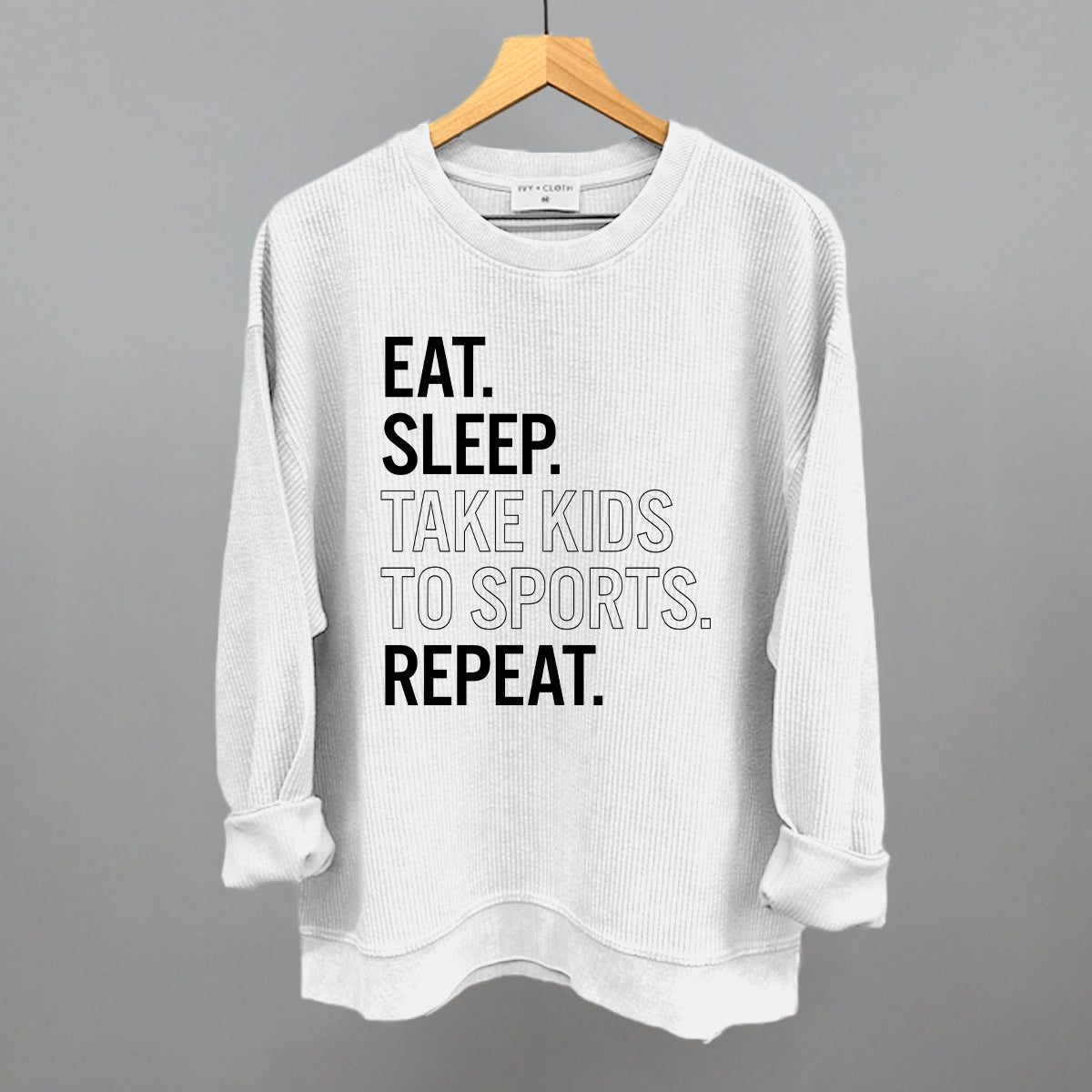 White corded crew sweatshirt with text on a hanger against a gray background