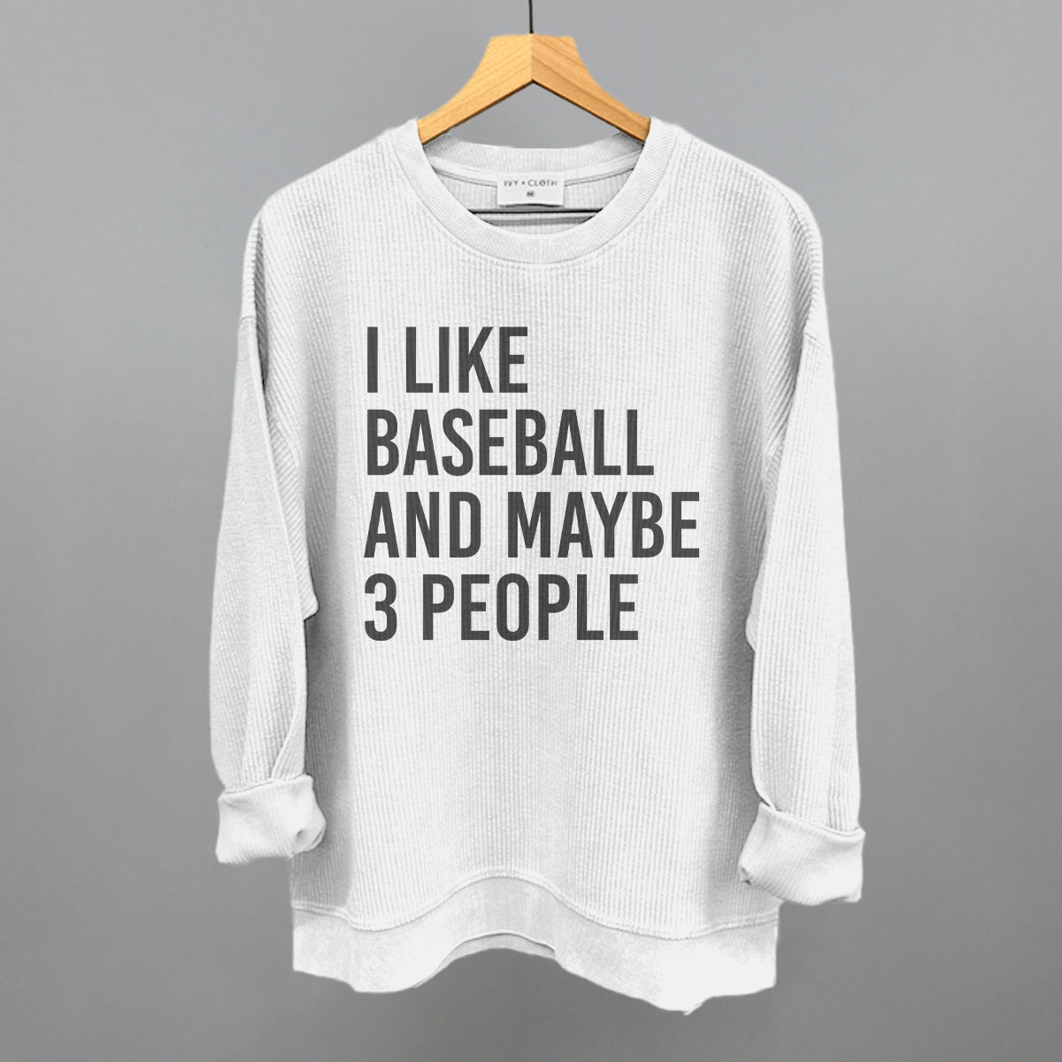 Collection of White sweatshirt with text 'I LIKE BASEBALL AND MAYBE 3 PEOPLE' on a hanger against a gray background in a gallery layout