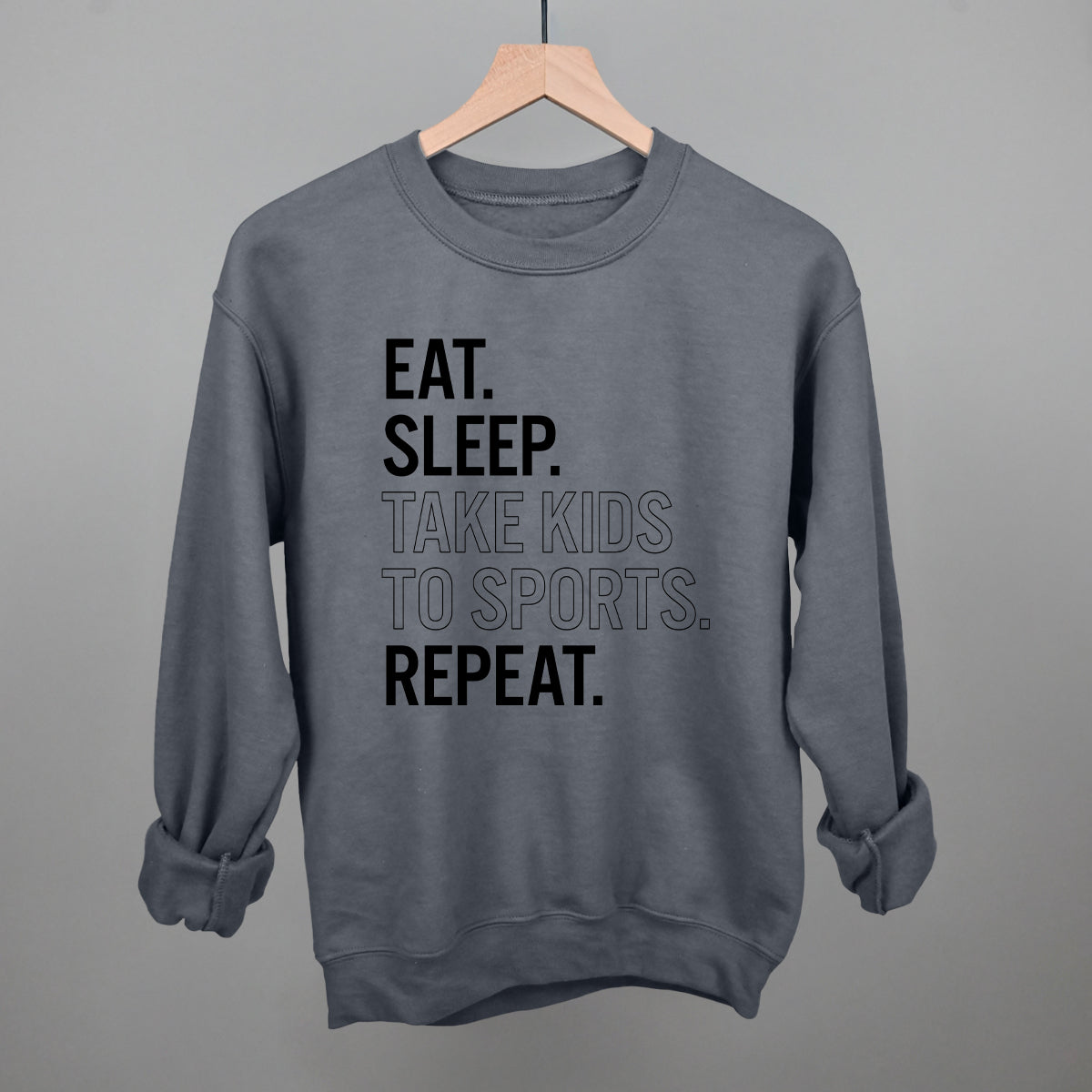 charcoal comfort colors sweatshirt with text 'EAT. SLEEP. TAKE KIDS TO SPORTS. REPEAT.' on a gray background