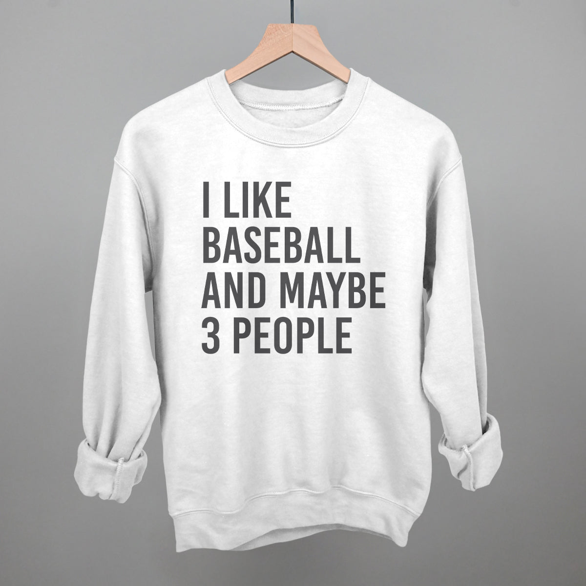 Collection of White sweatshirt with text 'I LIKE BASEBALL AND MAYBE 3 PEOPLE' on a hanger against a gray background in a gallery layout