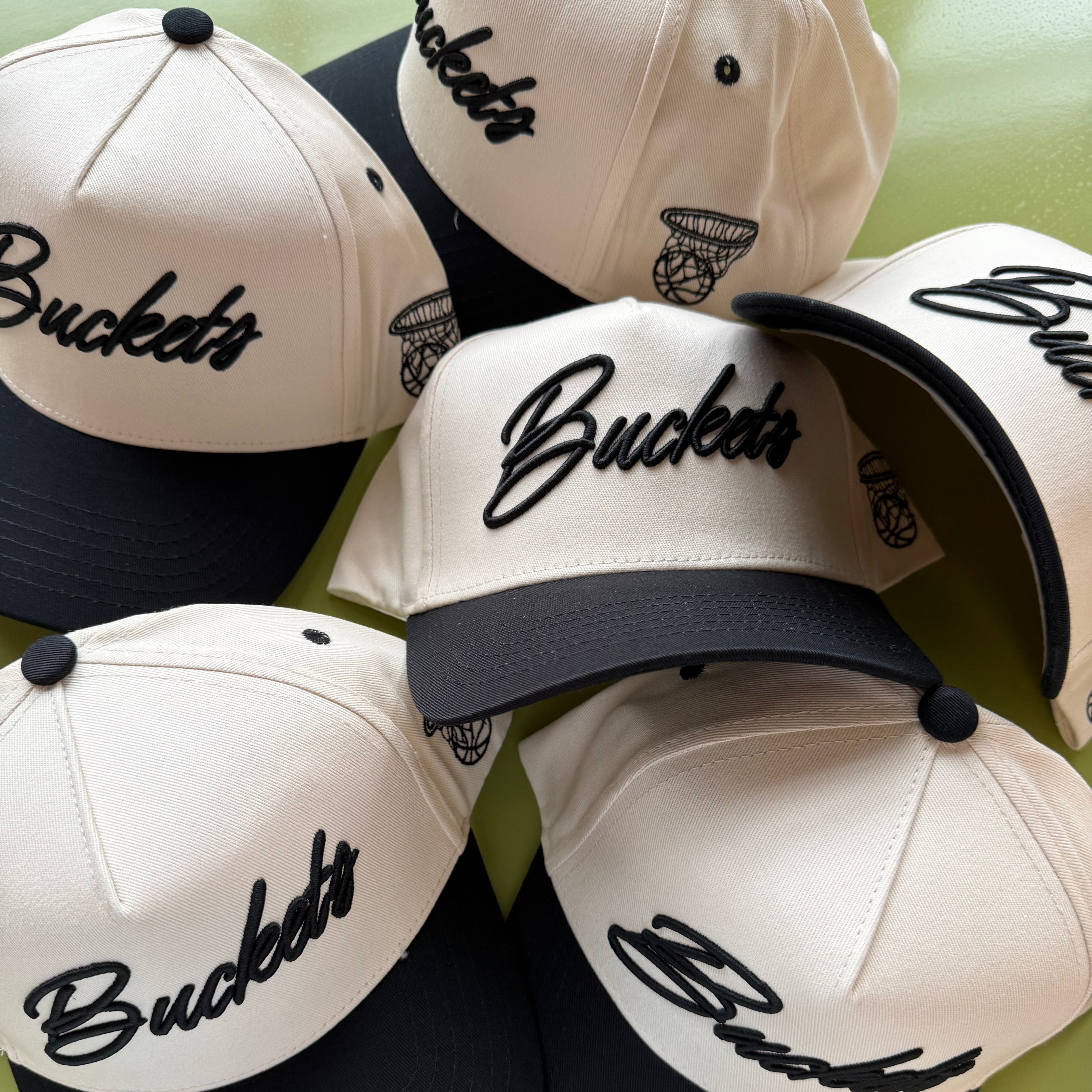 Collection of Collection of 'Buckets' branded caps on a green background in a gallery layout