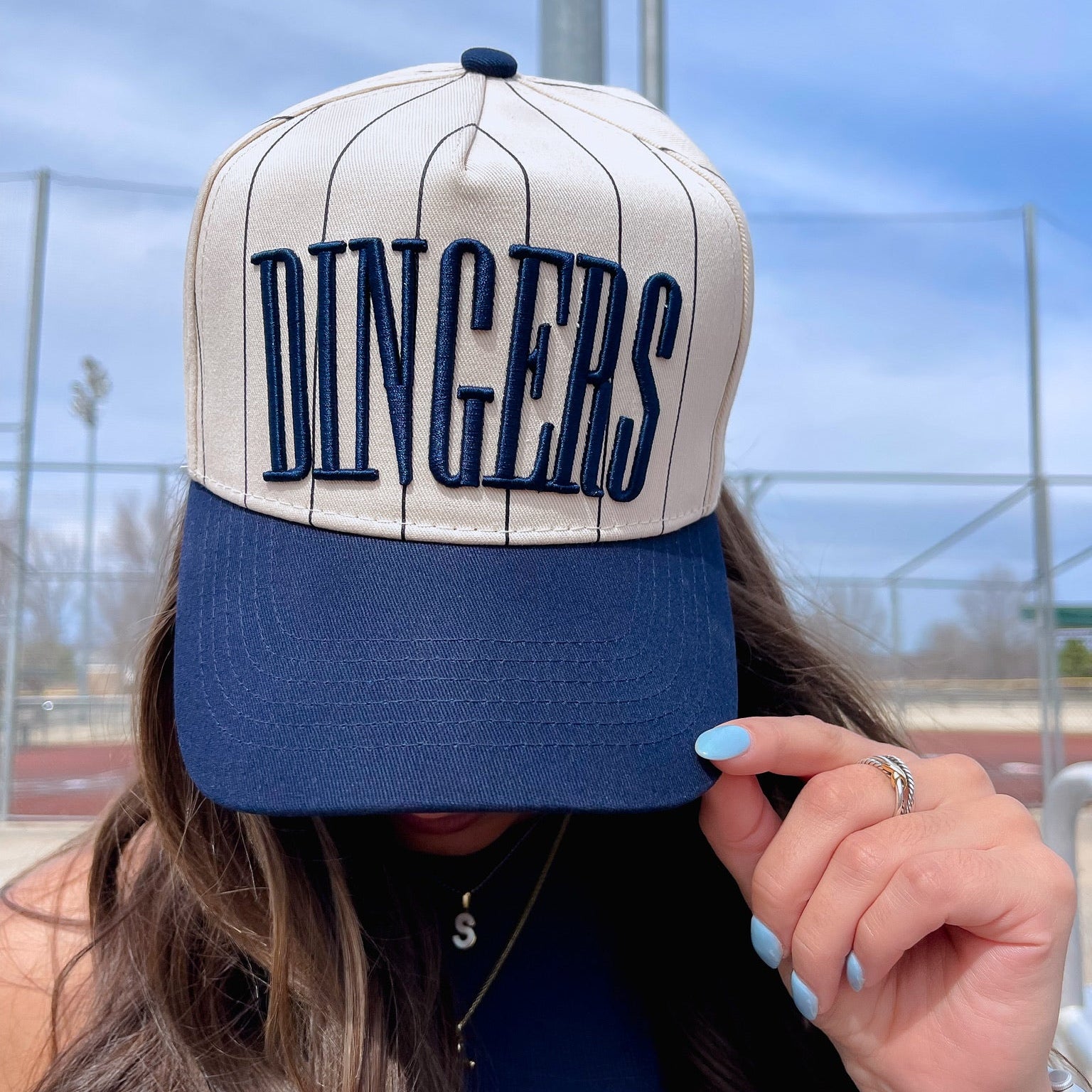 Person wearing a cap with 'DINGERS' text outdoors
