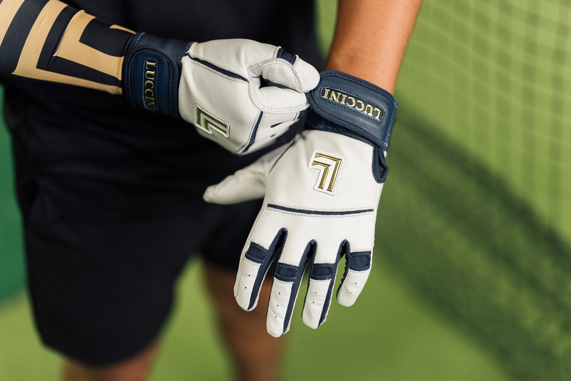 Collection of Person wearing Lucchini branded batting gloves on a blurred green background in a gallery layout