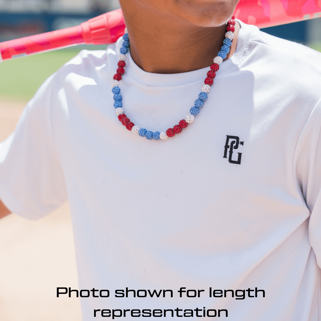 Person wearing a white t-shirt with a logo and a colorful beaded necklace outdoors.