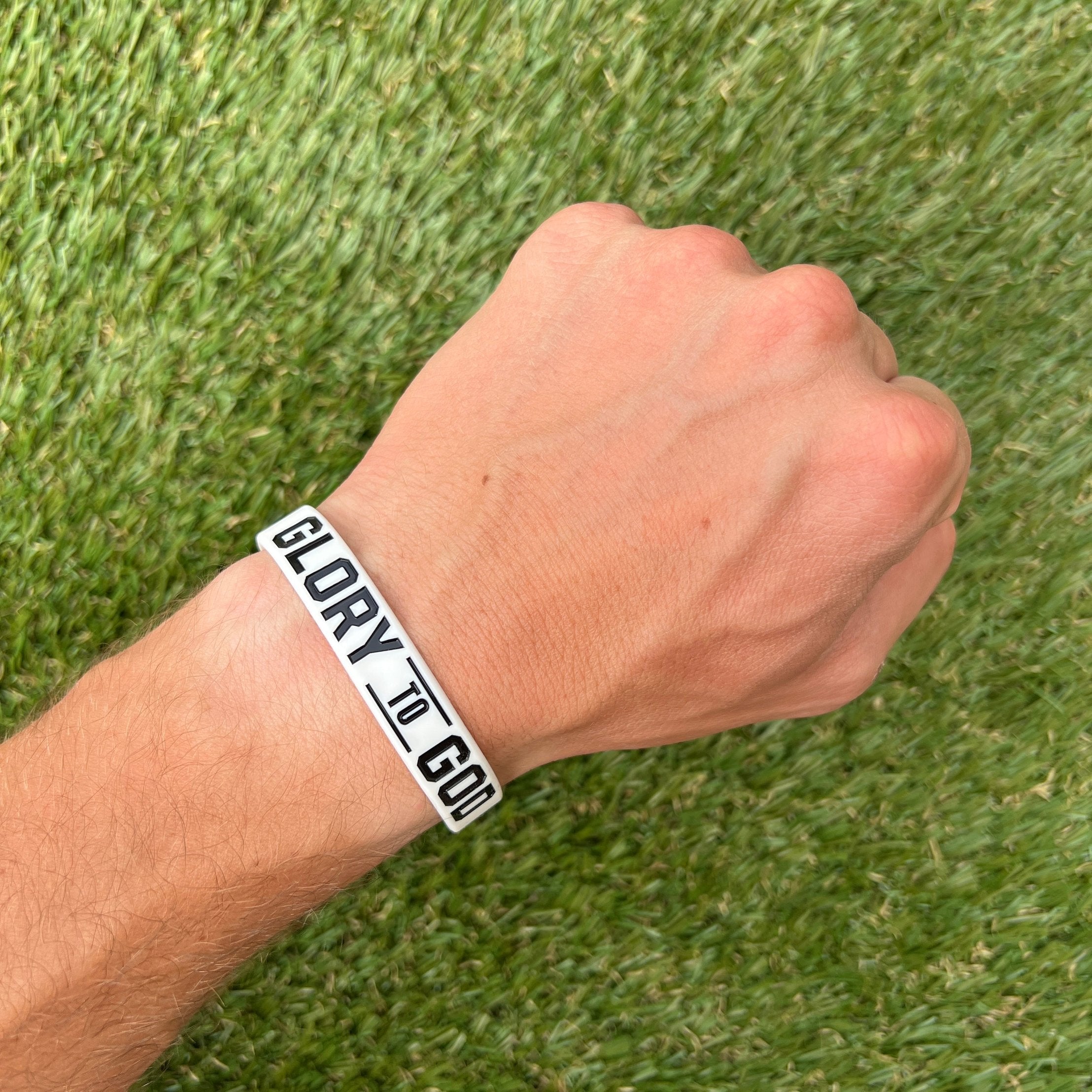 Collection of Hand wearing a 'GLORY TO GOD' bracelet on a grass background in a gallery layout