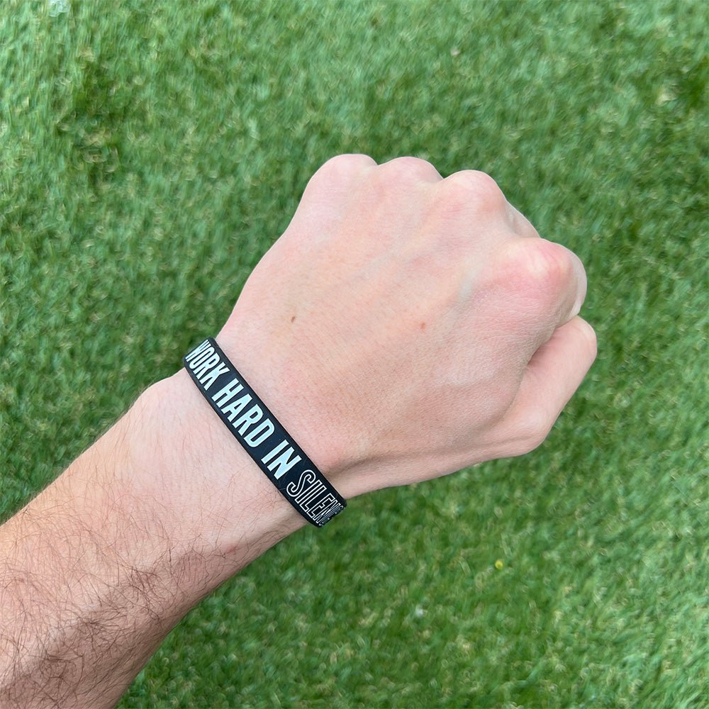 Collection of Hand wearing a black wristband with text on a grass background in a gallery layout