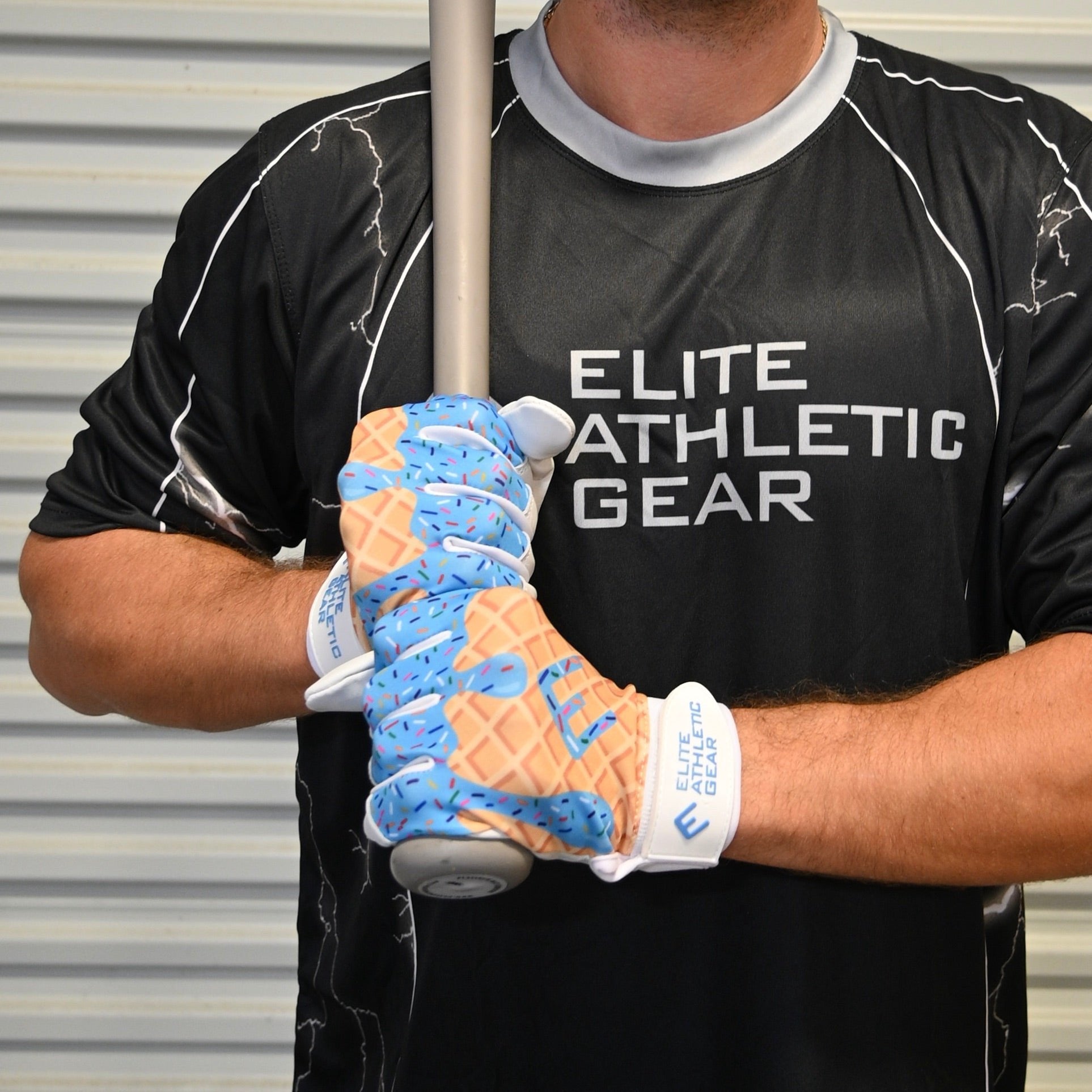 Collection of Person wearing a black 'Elite Athletic Gear' shirt holding a baseball bat with a blue and orange glove. in a gallery layout