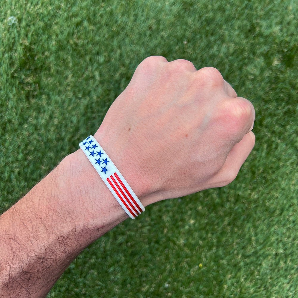 Collection of Hand wearing a wristband with an American flag design on a grass background in a gallery layout
