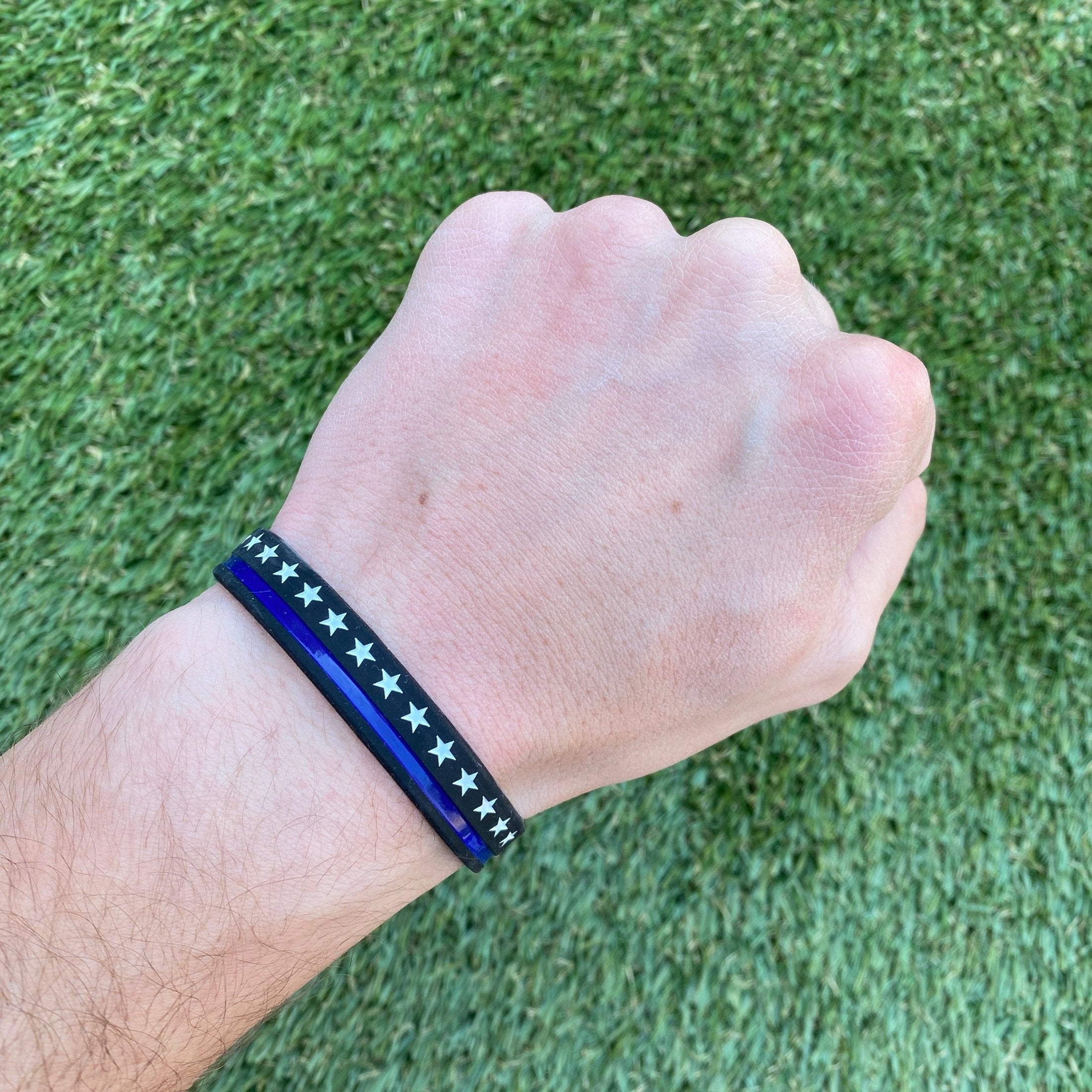 Collection of Hand wearing a blue and black bracelet with star pattern on grass background in a gallery layout